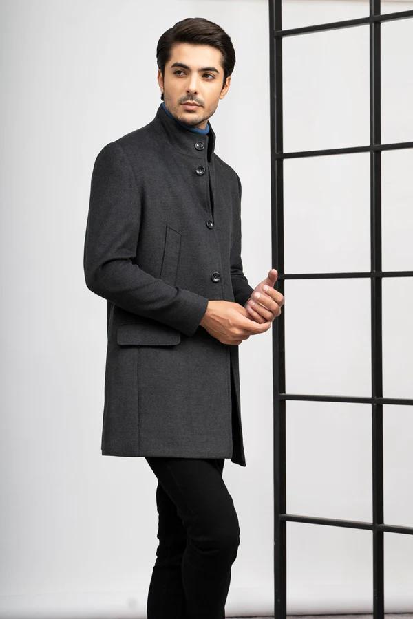 Stylish men's charcoal gray pea coat with button closure, worn by a handsome male model posing in front of a large window.