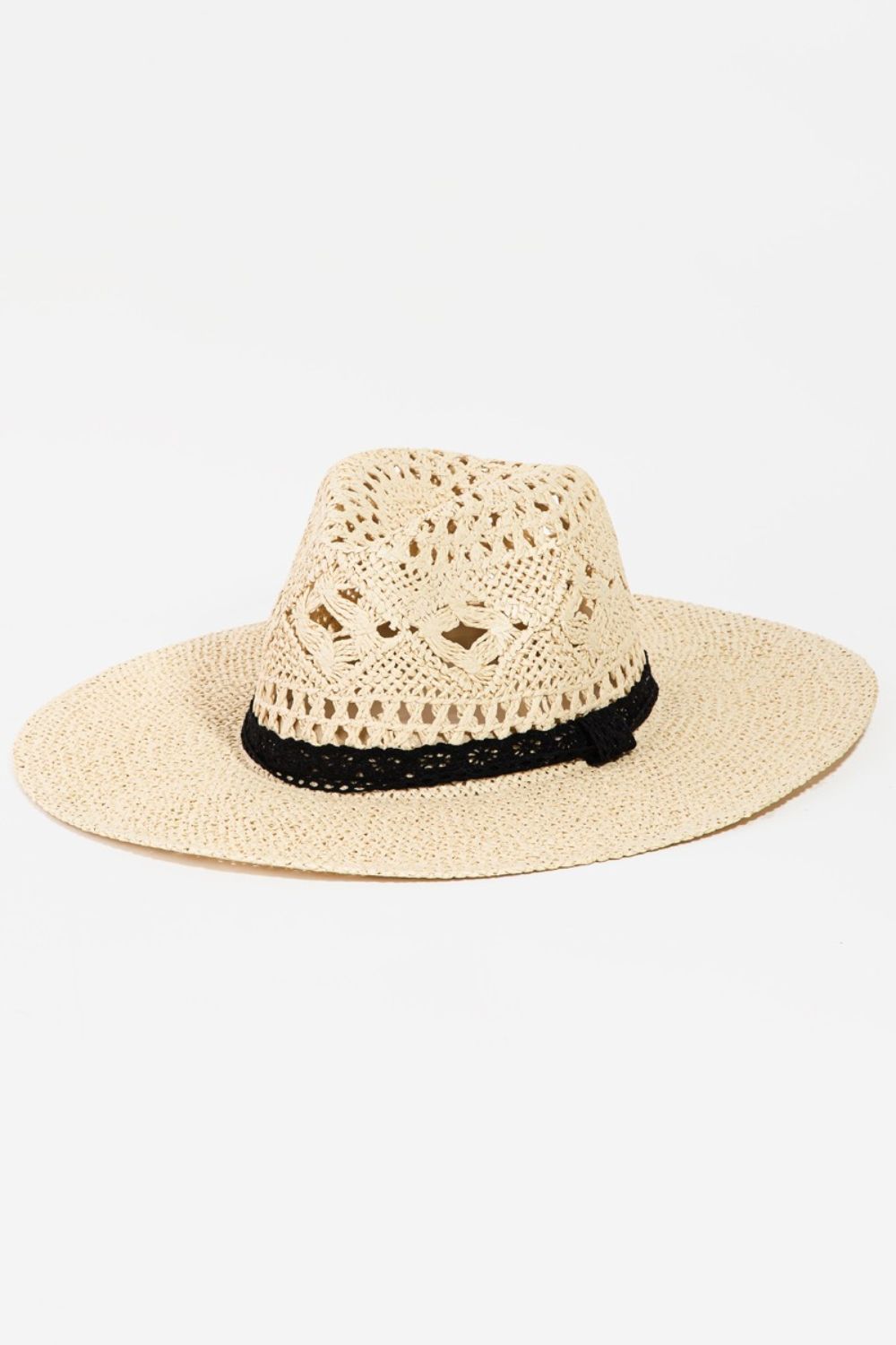 Elegant beige wide-brimmed hat with openwork lace detail and contrasting black trim, showcasing a stylish and sophisticated accessory.