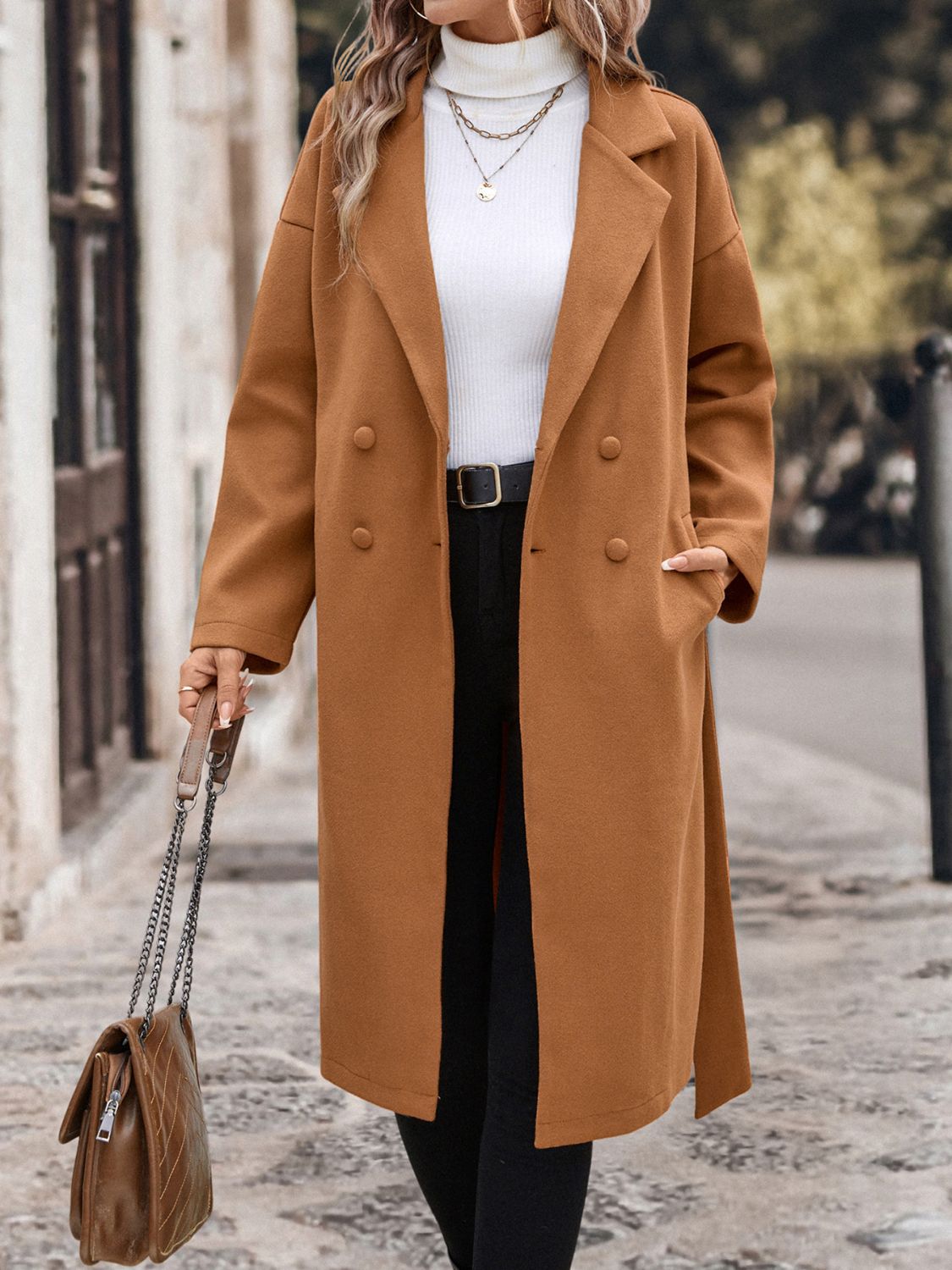 Stylish camel wool coat with dropped shoulders and tie waist, worn by a fashionable woman while walking through a city street.