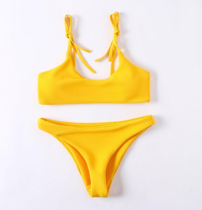 Vibrant yellow women's bikini with tie-front top and high-cut bottom, stylish swimwear for the beach or poolside.