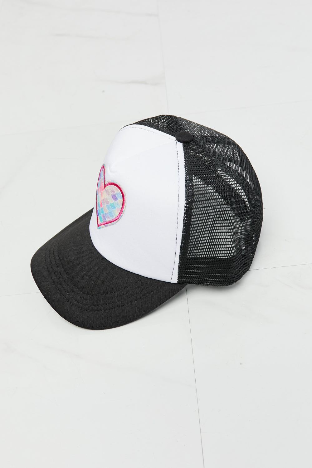 Stylish black and white trucker hat with a pink heart design, perfect for casual wear or accessorizing an outfit.