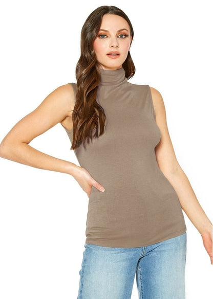 Fitted women's sleeveless turtleneck top in neutral beige tone, worn by model with long wavy brown hair in casual pose against white background.