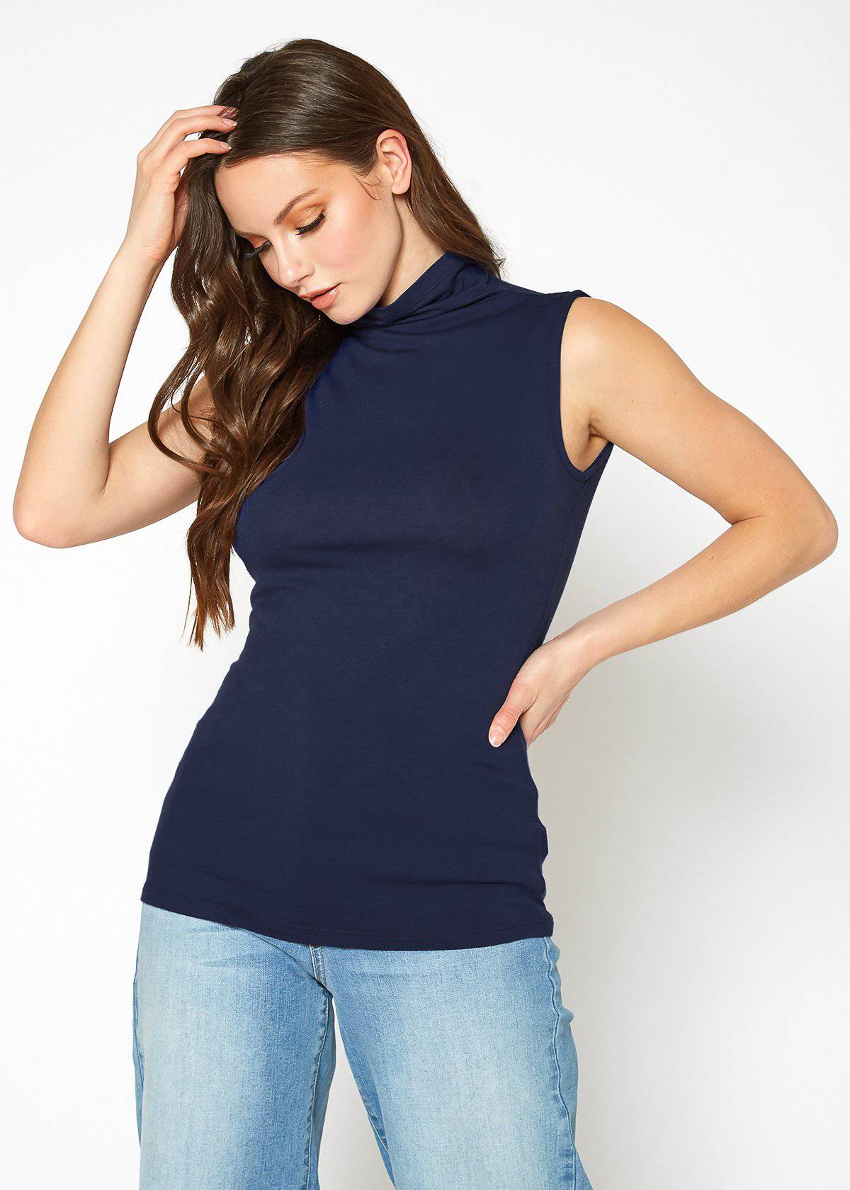 Sleeveless navy blue turtleneck fitted top for women, showcased by a model with long brown hair posing against a plain white background.