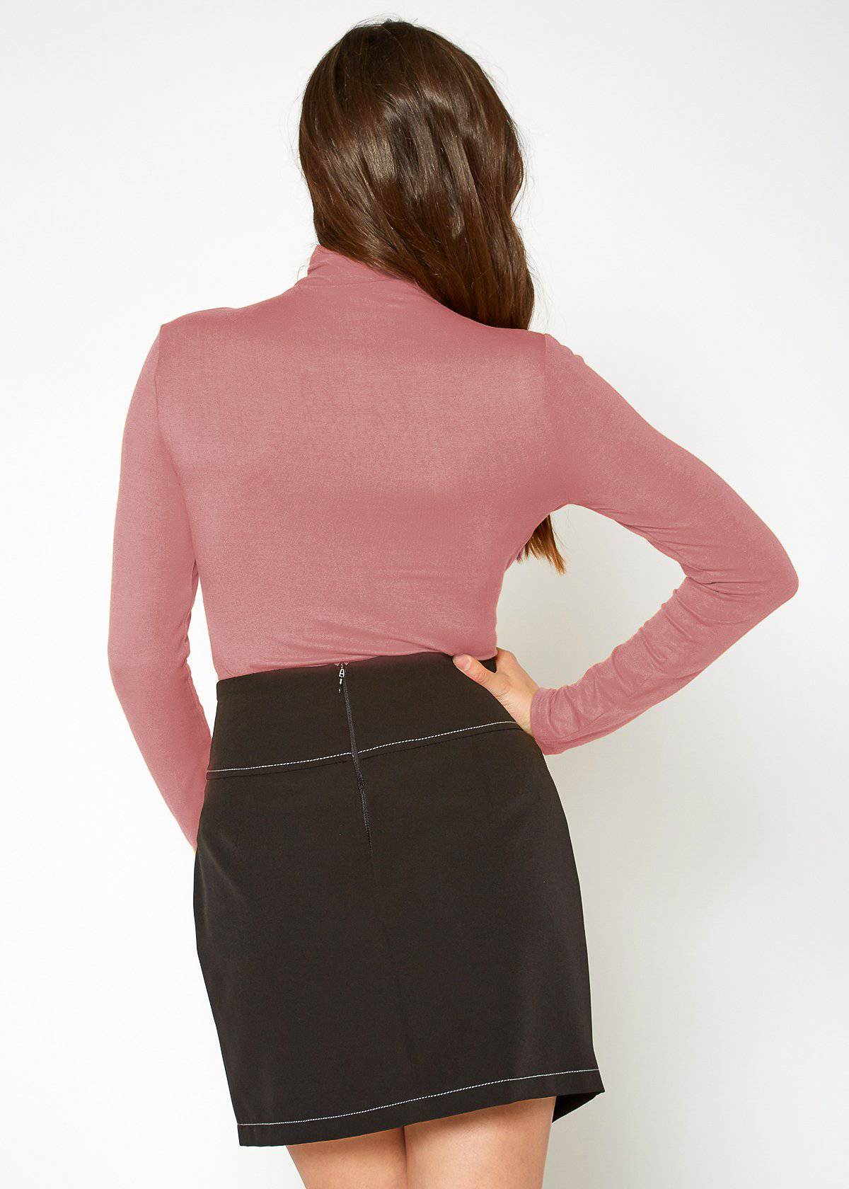 Fitted pink turtleneck top with long sleeves and black mini skirt