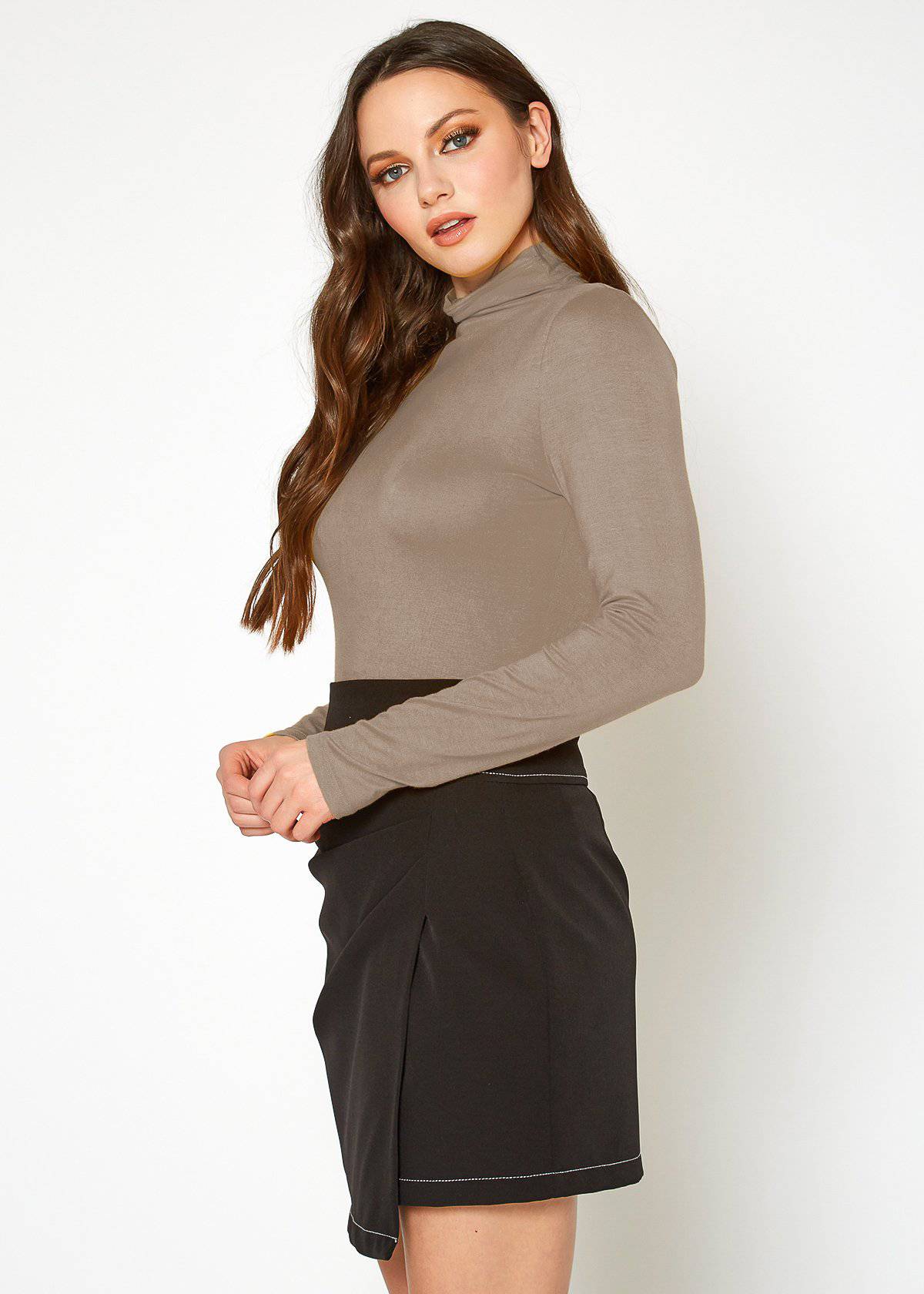 Beige long-sleeve turtle neck fitted top on a woman with long brown hair