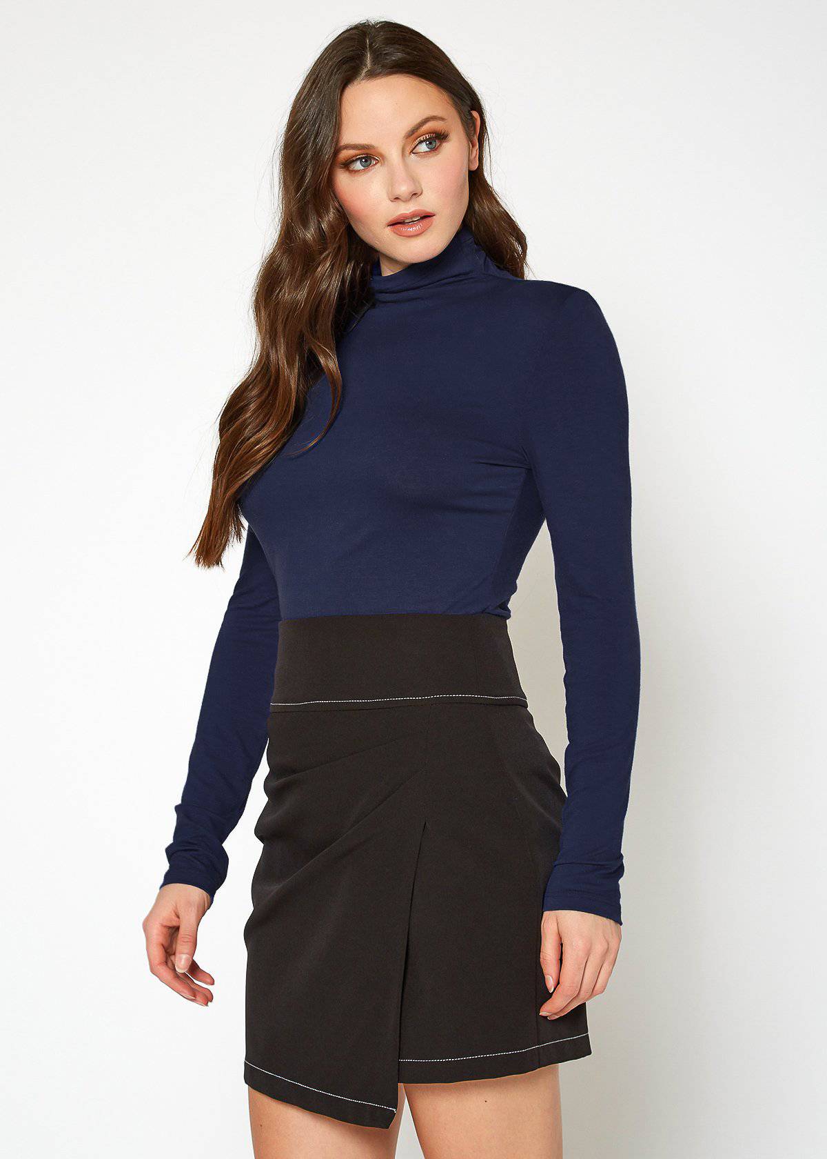 Elegant navy blue women's top with turtleneck and fitted silhouette, featured on a model with long wavy hair posing against a white background.