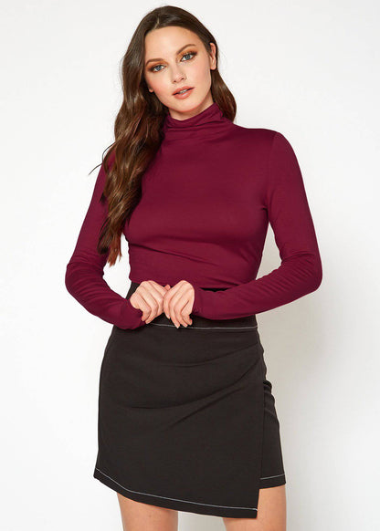 Burgundy turtleneck top with long sleeves, worn by a young woman with long brown hair against a plain background.