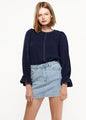 Navy blue puff shoulder top with bell cuff sleeves by Lemon Hera, worn with light denim mini skirt on a female model against a white background.