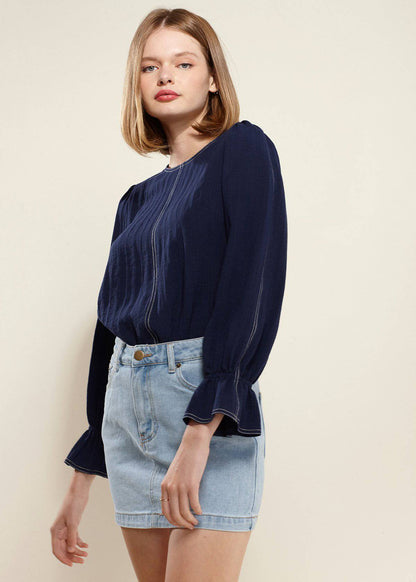 Navy blue blouse with puff sleeves and bell cuffs, worn by a woman with long blonde hair.