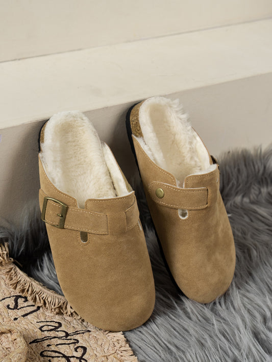 Cozy Suede Slippers on Plush Rug: Tan suede round-toe slippers with soft faux fur lining, sitting on a grey shaggy rug.