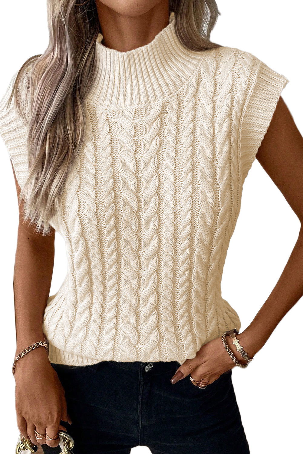 Cozy cable knit cream-colored high neck sweater vest with textured patterns, displayed on a female model against a plain background.