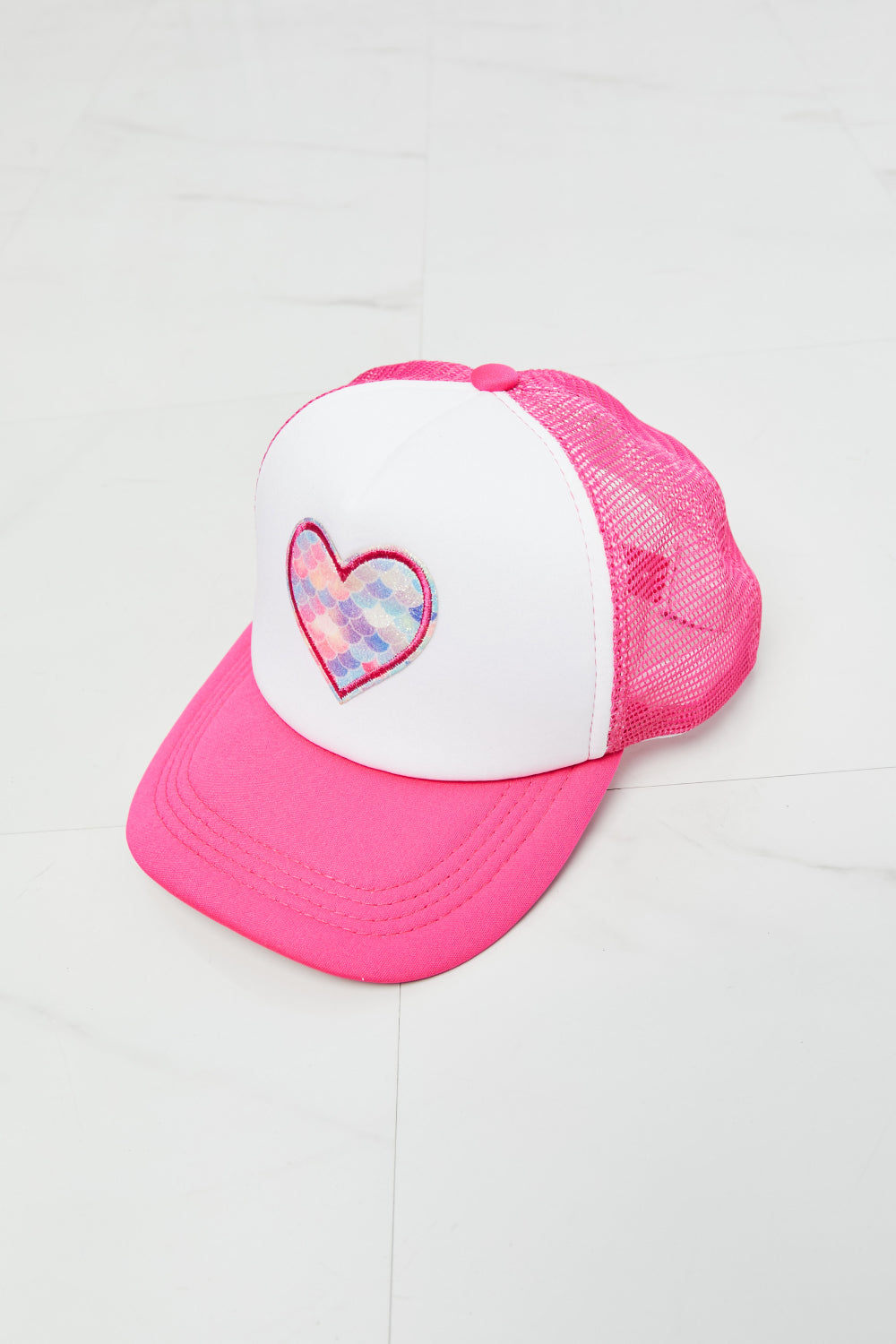 Vibrant pink and white trucker hat with heart-shaped applique for fashionable accessorizing.