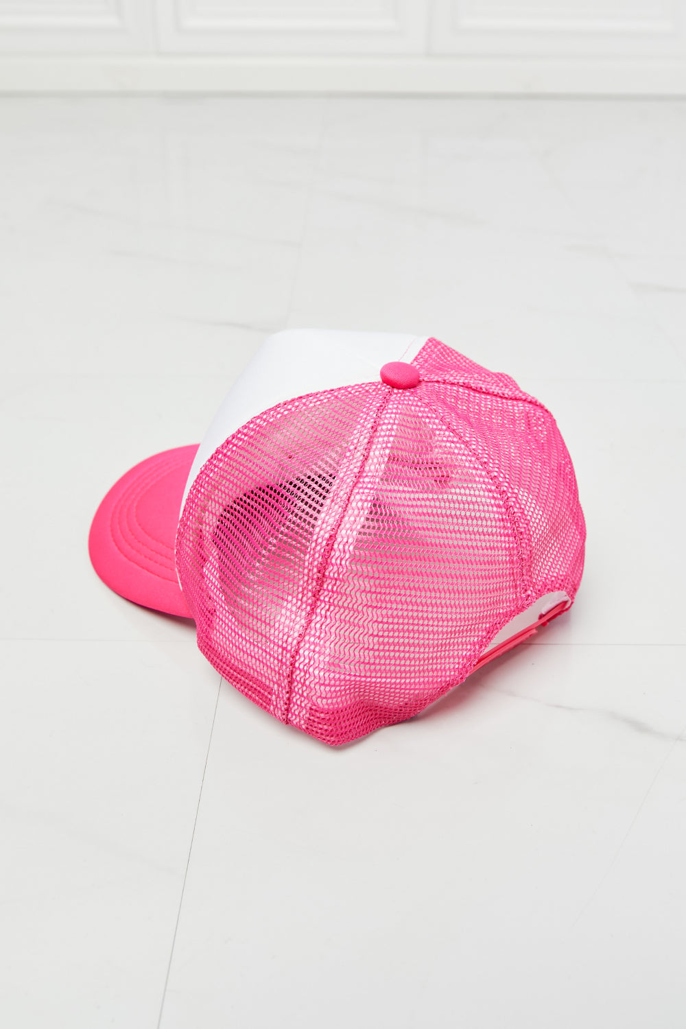 Bright pink mesh trucker hat with bow detail, perfect for casual fashion.