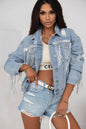 Distressed denim jacket with sequin fringe trim, paired with ripped denim shorts, creating a stylish, casual look.