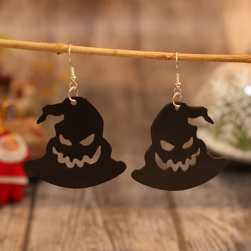 Spooky Witch Hat Earrings - Leather silhouettes of witches' hats with frightening faces hang from a rustic wooden frame, creating a whimsical Halloween accessory.