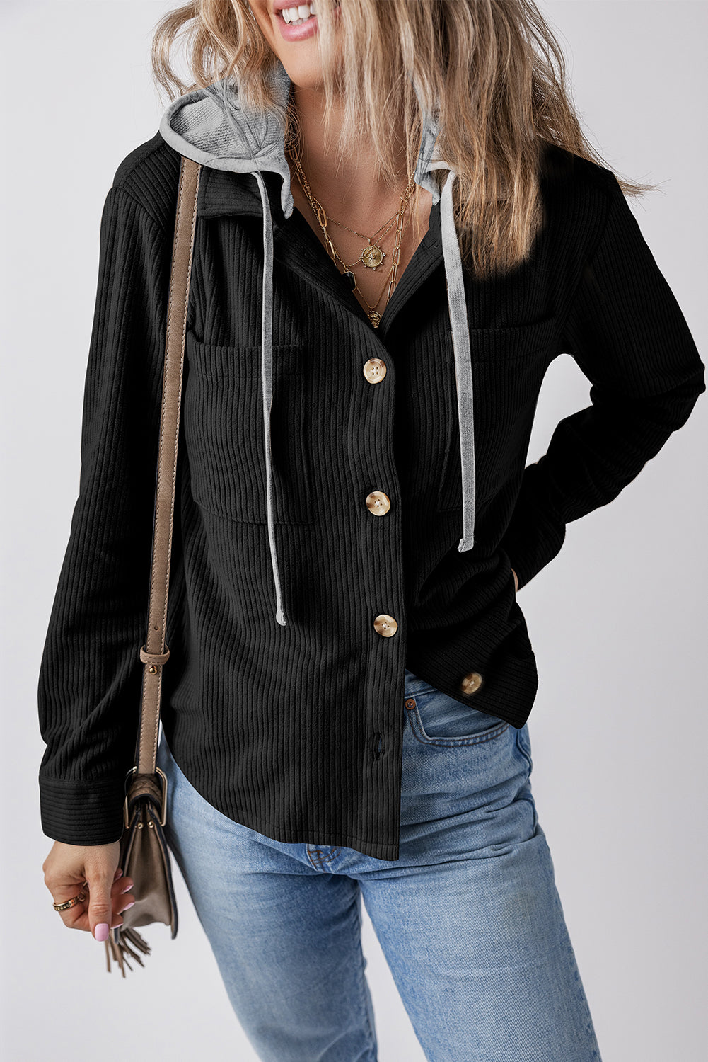 Stylish black corduroy shacket with drawstring pockets, worn by a smiling woman against a plain background.