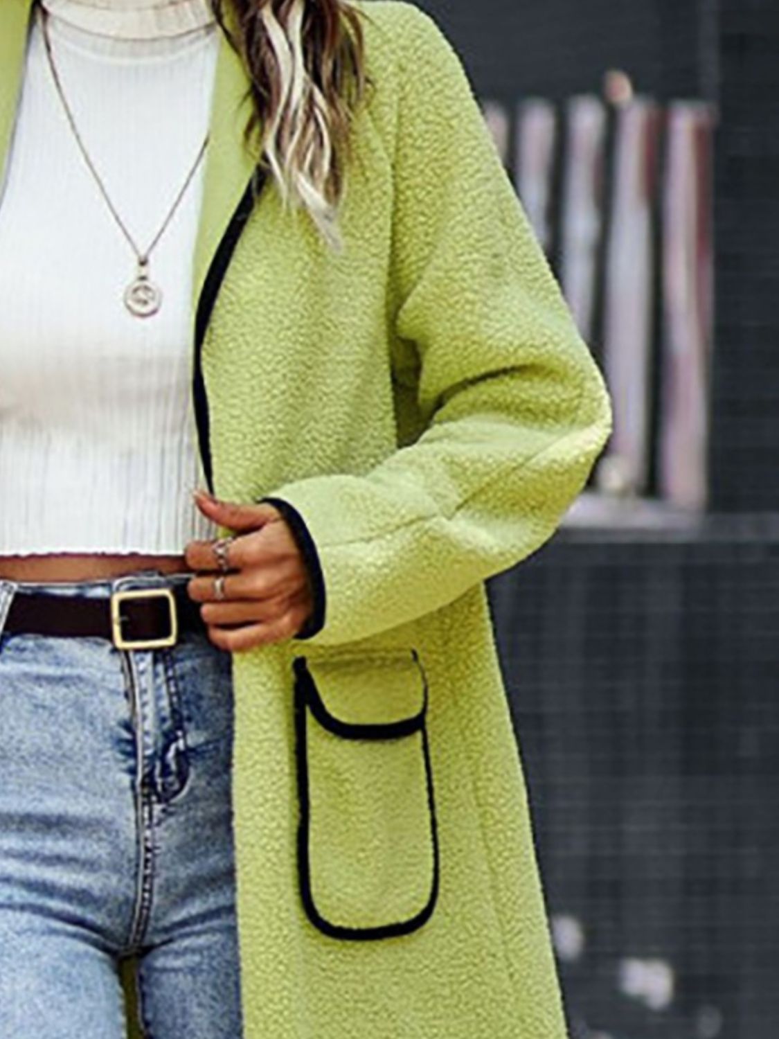 Cozy green oversized sweater with pockets, paired with high-waisted blue jeans, accentuating the model's casual chic style.