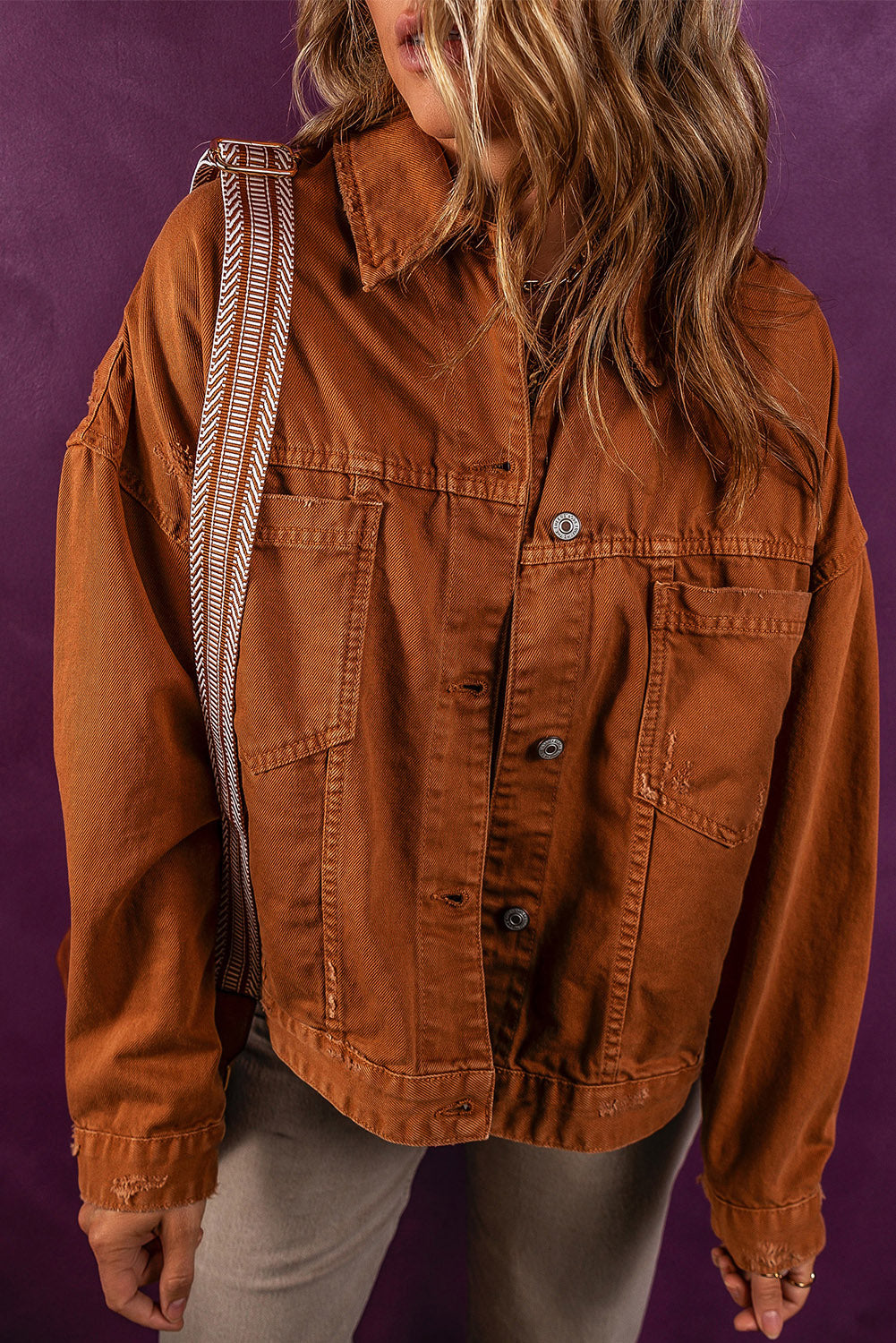 Collared button-up denim jacket in warm autumn hue, featuring waist pockets and relaxed fit.