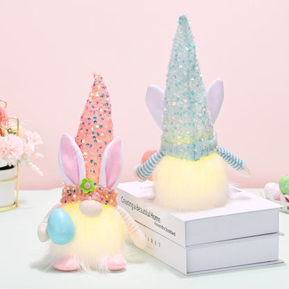 Whimsical Easter decor featuring pastel-colored sequined hats, a fluffy plush gnome figure, and floral accents on a light pink background.