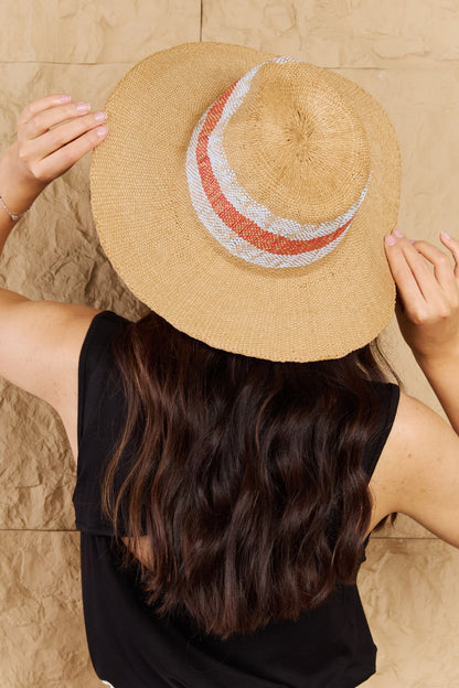 Natural straw sun hat with vibrant orange and white striped band for stylish sun protection.