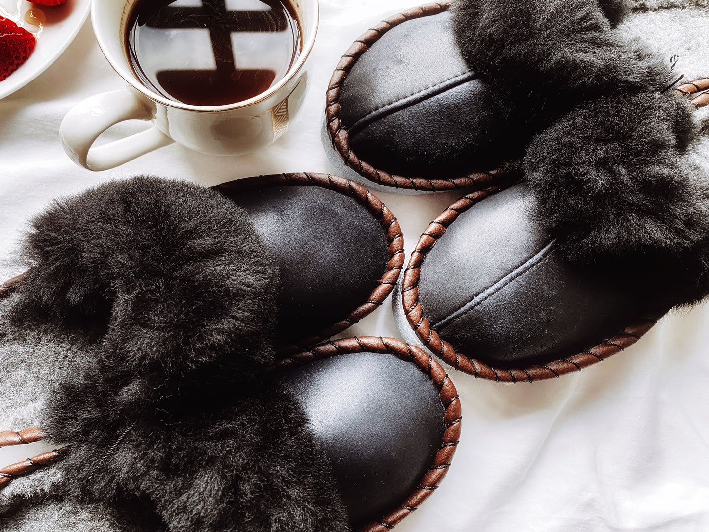 Cozy black slip-on shoes with plush fur trim, showcasing a stylish and comfortable design. These limited edition slippers from the Erin Thalassa brand exude a luxurious aesthetic, making them an ideal choice for the fashion-conscious consumer.