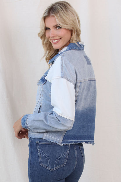 Colorblock Distressed Denim Jacket by Trendsi 

The image shows a woman wearing a stylish denim jacket with a distressed, colorblocked design. The jacket features a casual and trendy look, with a button-up front and frayed edges. The model's confident, smiling expression complements the fashionable outerwear piece.