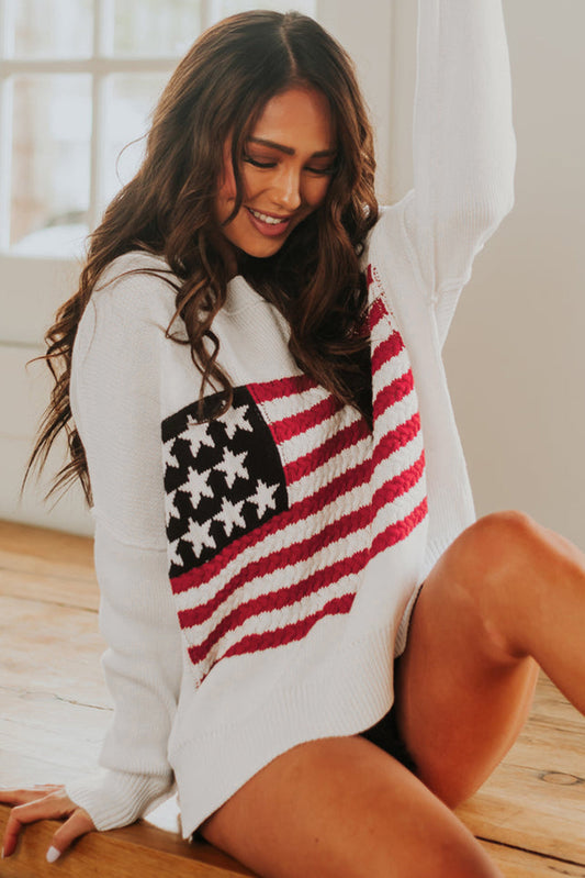 Cozy American flag cable knit sweater adorning smiling woman against bright window backdrop.