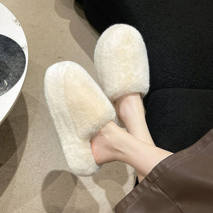 Cozy fluffy white round toe slippers resting on a dark surface