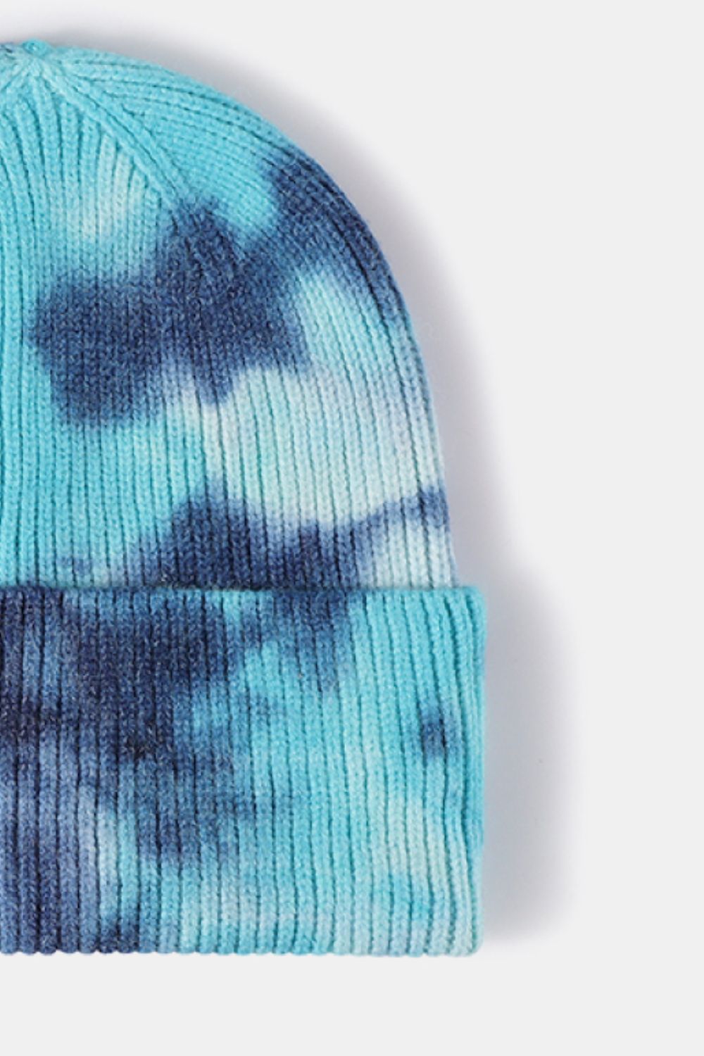 Trendy tie-dye cuffed rib-knit beanie hat in shades of turquoise and navy blue.