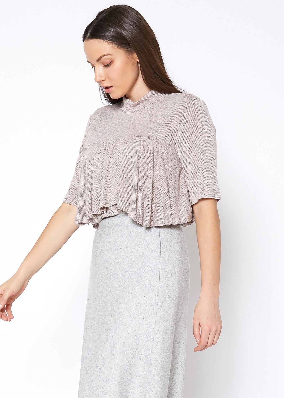 Short-sleeved ruffled top in a soft neutral color, worn by a young woman with long dark hair, against a plain white background.