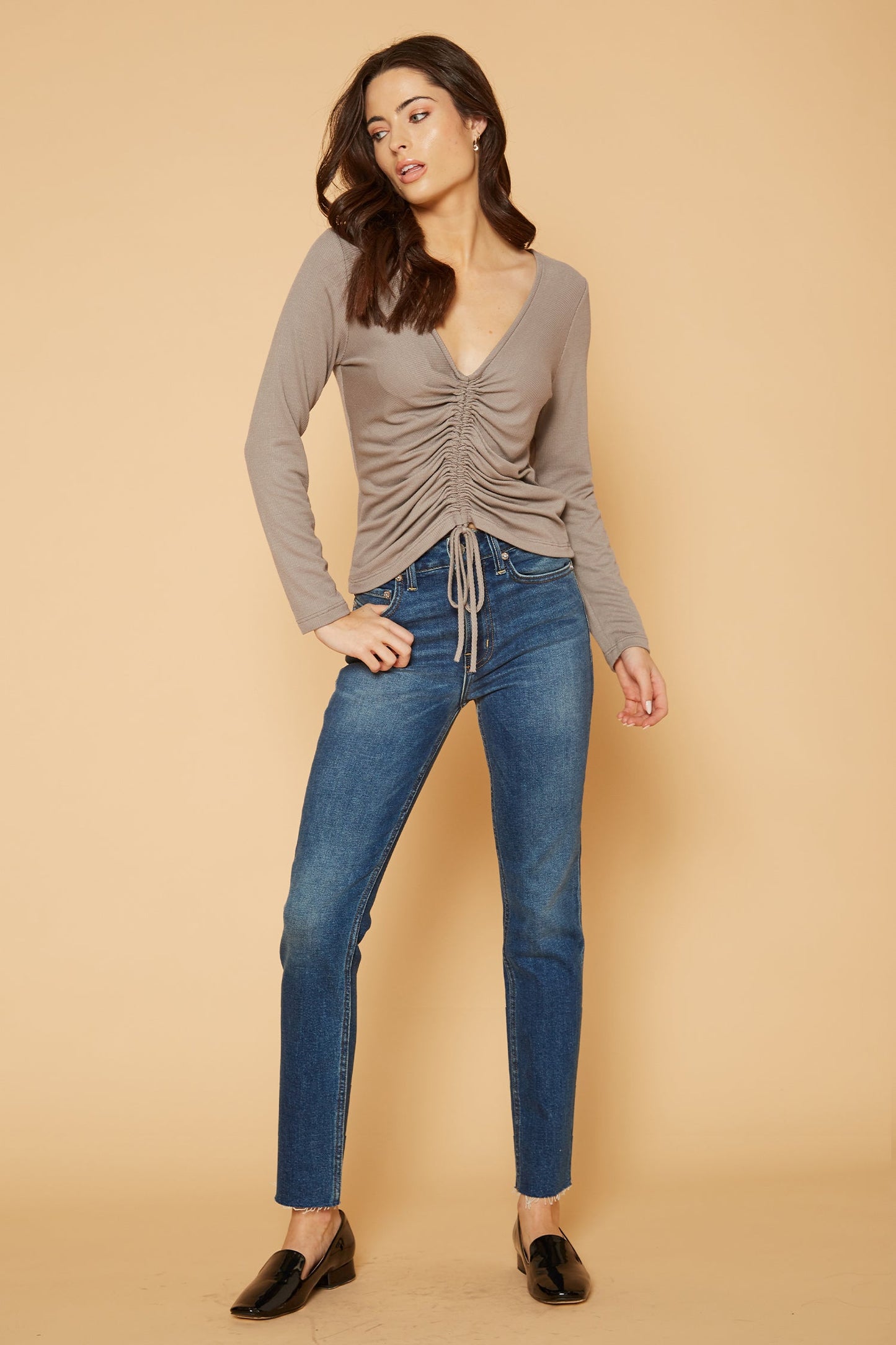 Stylish ruched v-neck top with a casual vibe, paired with classic blue jeans for a chic everyday look.