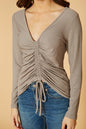 Ruched beige V-neck top with long sleeves, worn with blue denim jeans