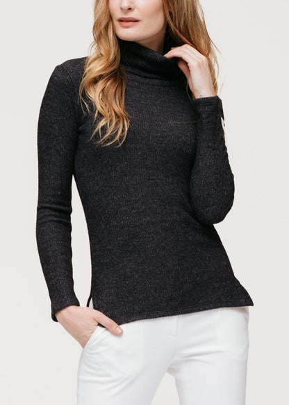 Soft, ribbed-knit black women's sweater top with a high turtleneck collar, showcased on a female model with long blonde wavy hair.