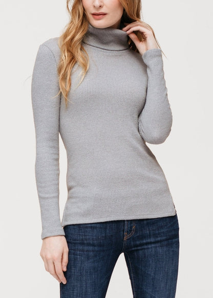 Soft turtle neck ribbed knit sweater top by Lemon Hera, featured on a woman with long wavy hair against a plain background.