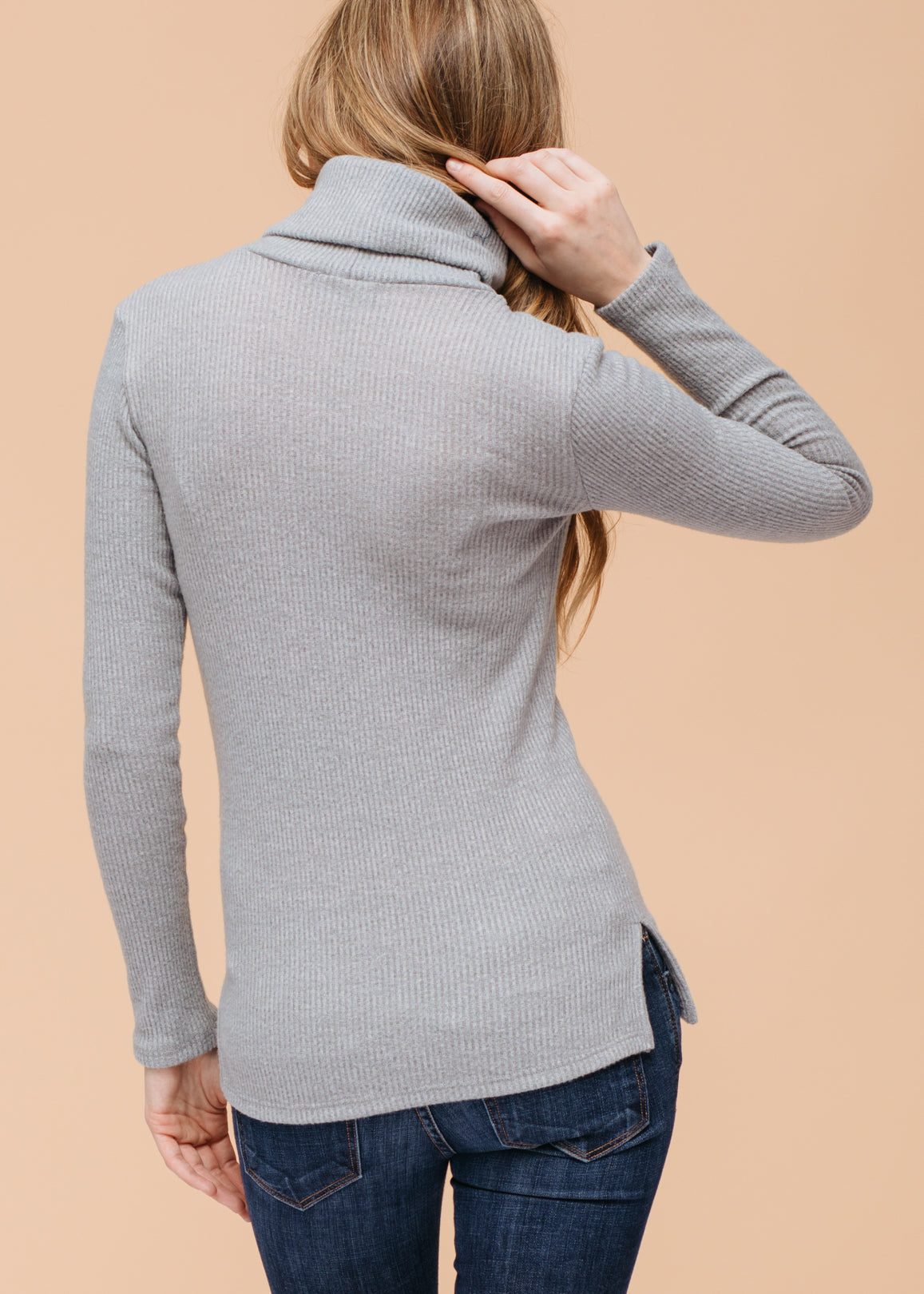 Soft ribbed knit sweater in neutral grey, complemented by a cozy turtleneck collar.