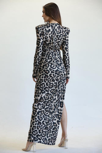 Elegant leopard print pattern dress showcased on a female model. The long-sleeved maxi dress features a high slit and a cinched waist, creating a flattering silhouette. The striking animal print design adds a touch of sophistication to this chic and fashionable piece.