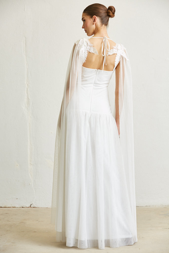 Elegant white dress with lace details, open back, and flowing cape sleeves on a female model against a plain white background.