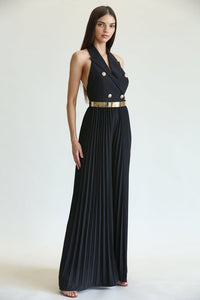 Elegant gold-buttoned black jumpsuit with pleated maxi skirt, showcasing a woman's sophisticated style.