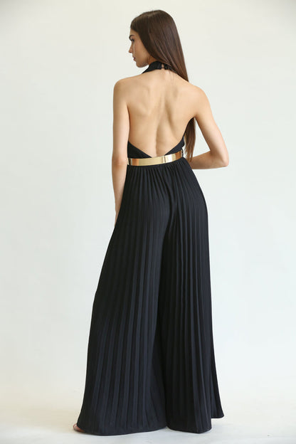 Elegant black jumpsuit with pleated details and metallic belt, showcasing the model's back and long dark hair.