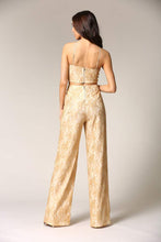 Load image into Gallery viewer, Gold lace pant suit with flared legs and spaghetti straps, showcased by the model facing away from the camera