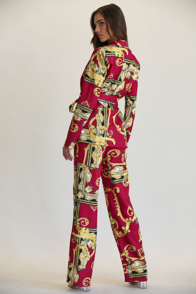 Ornate floral patterned women's blazer and pant set in vibrant red and gold tones, showcased on a female model standing against a plain background.