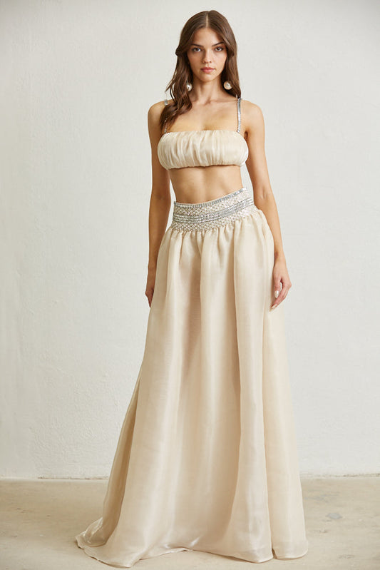 Elegant two-piece set with beige crop top and flowing maxi skirt, showcasing the model's stylish and feminine look.