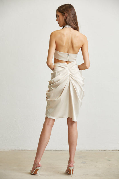 Elegant ivory dress with draped skirt and halter neckline, showcasing a woman's sophisticated and refined style.