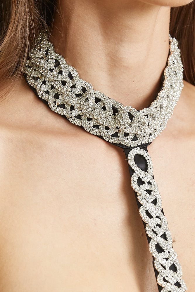 Elegant crystal necklace with intricate geometric design, adorning the model's neck against a soft skin backdrop.