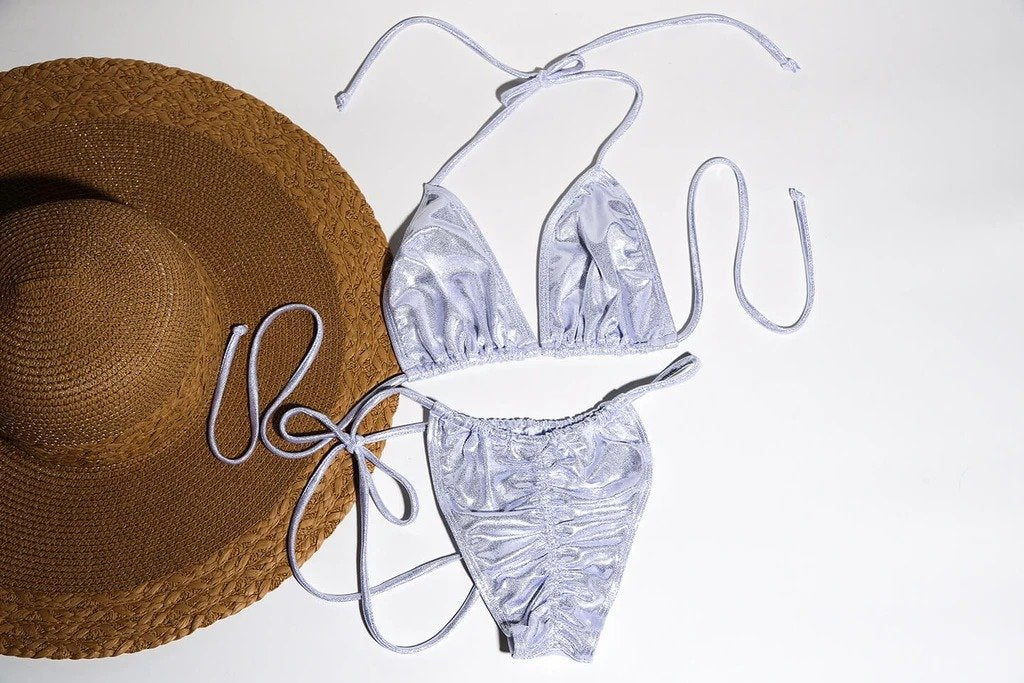 Stylish straw hat and elegant gray patterned swimsuit on plain background, showcasing fashionable women's summer apparel.