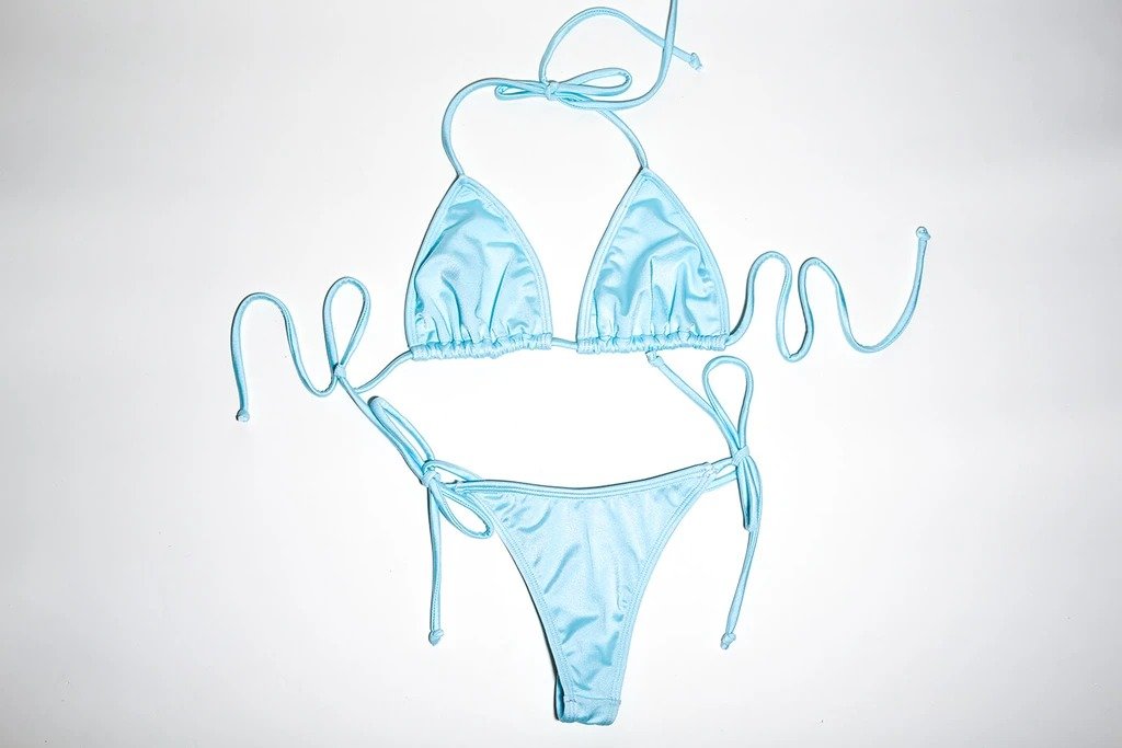 Teal-colored women's swimsuit with string bikini top and bottoms, placed against a plain white background.