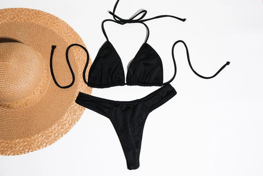 Stylish black bikini and straw sun hat, fashionable beach accessories.