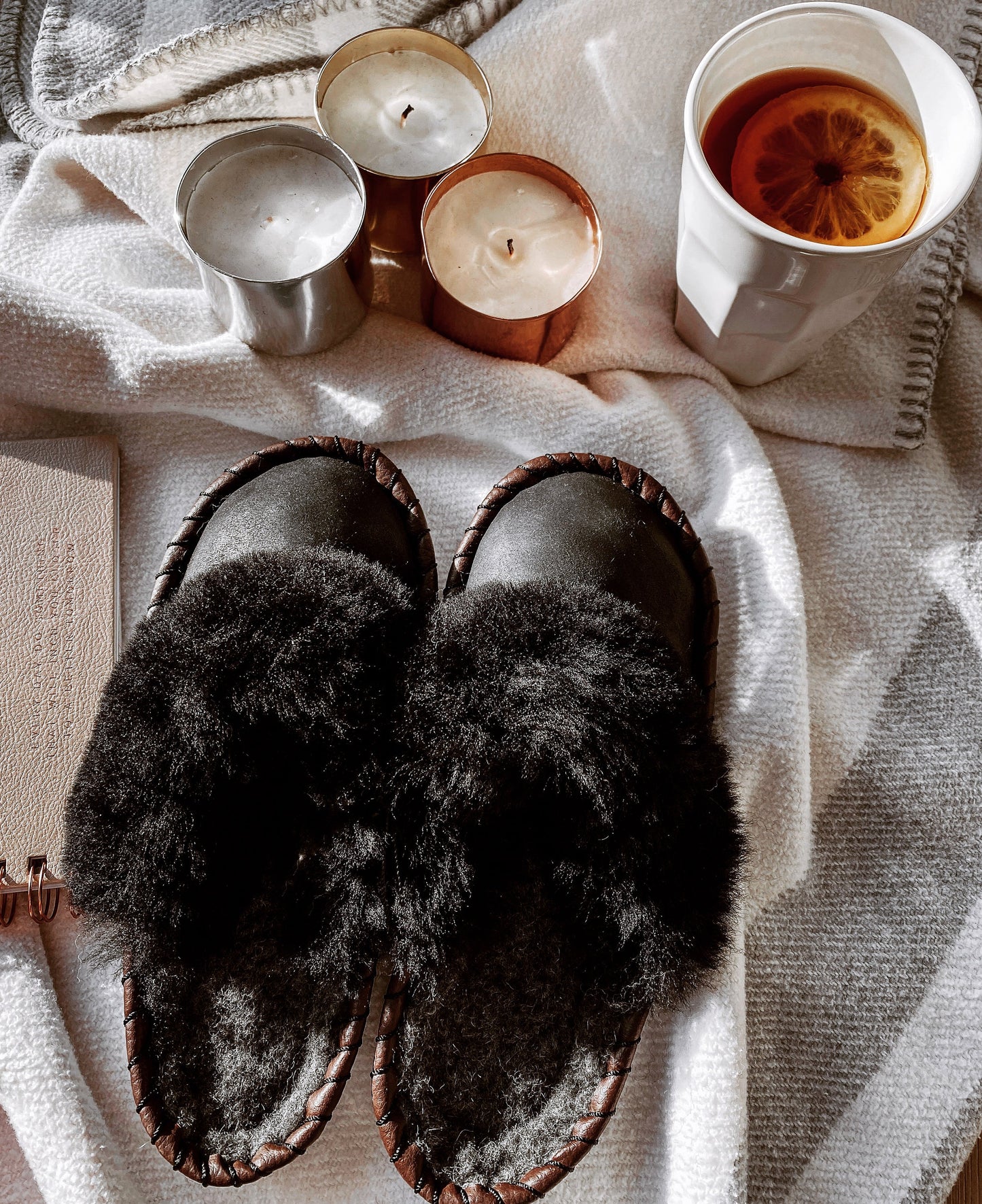 Cozy winter slippers, candles, and a warm drink - a comfy and relaxing scene perfect for chilly days at home.