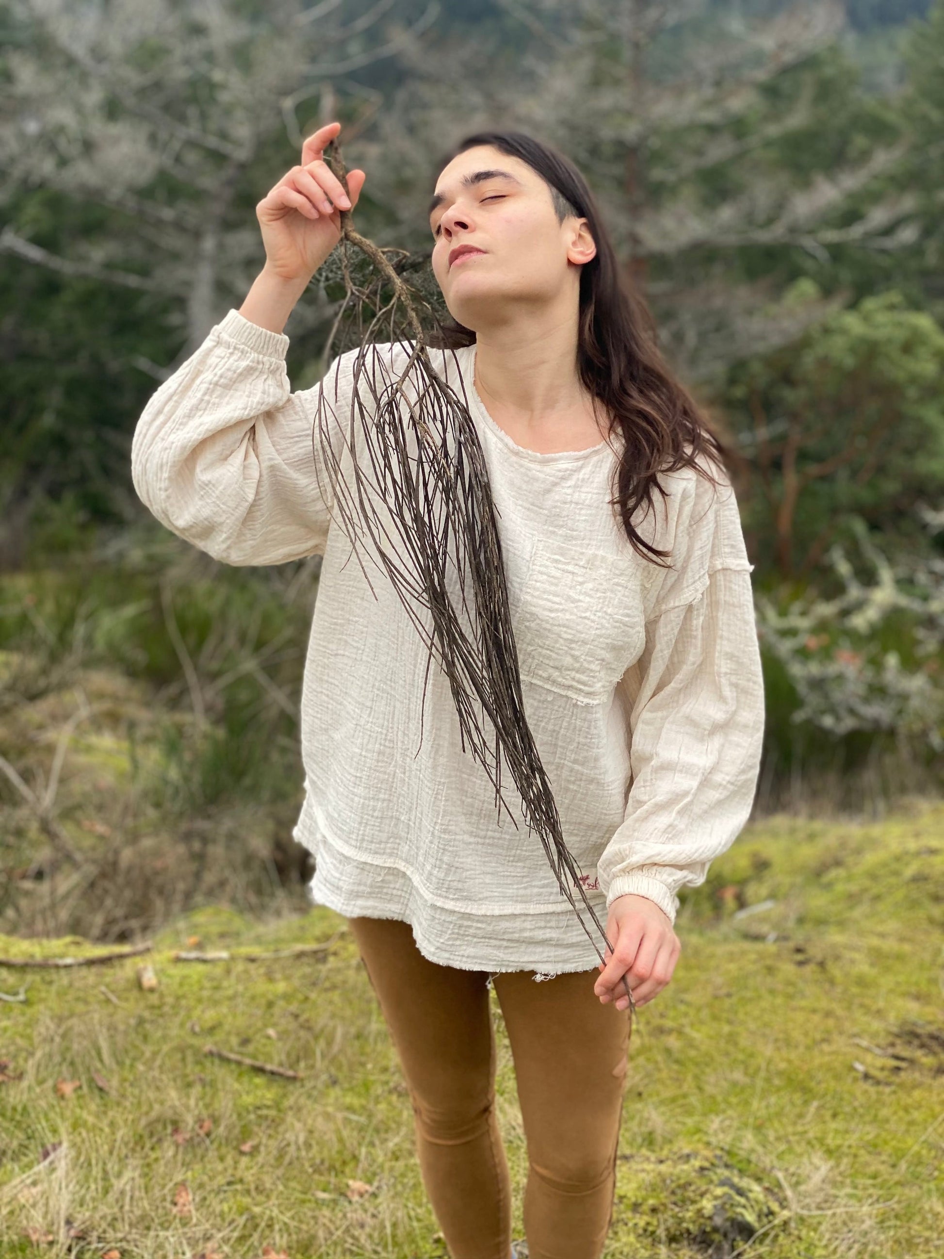 Casual young woman in natural setting holding plant stem