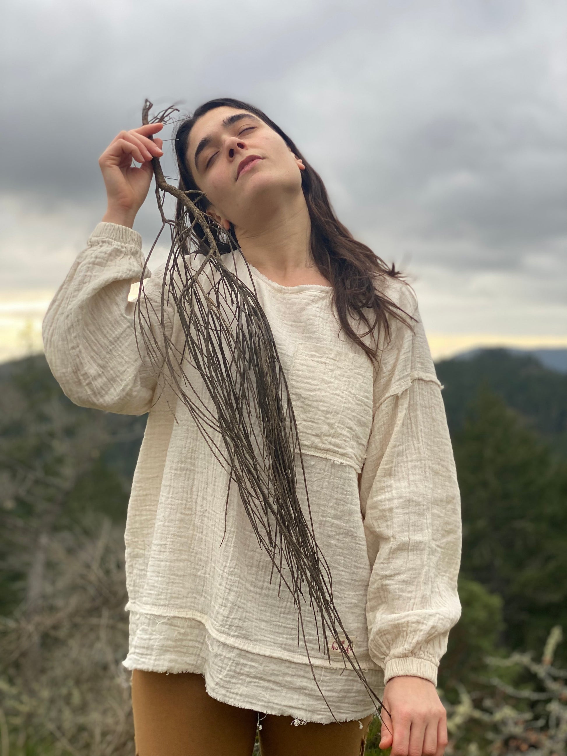 Woman wearing cream-colored organic cotton sweatshirt in natural outdoor setting